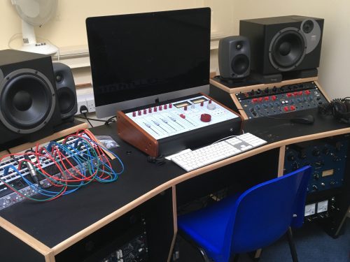 A sound desk, mixer, speakers and computer monitor are set up on a table.