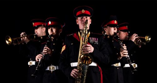 British Army Band Colchester in uniform playing instruments in front of a black background