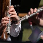 Close up image of two people playing flutes.