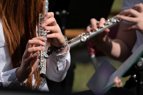 Close up image of two people playing flutes.